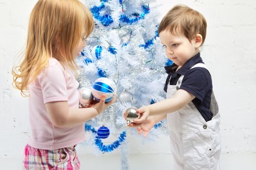two beautiful happy children decorate christmas tree