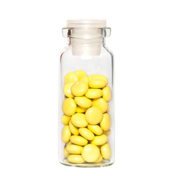 Yellow pills in the glass bottle close-up on a white background.
