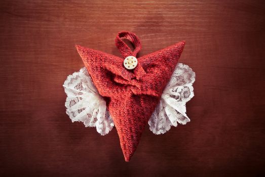 Red heart with white wings on wood background.