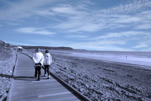 mother and daughter strolling along the beach boardwalk in Youghal county Cork Ireland