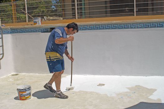 painter painting the bottom of a swimming pool                                