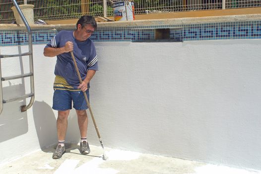 painter painting the bottom of a swimming pool                                