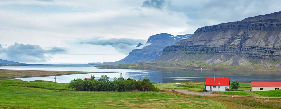 Rural beautiful summer landscape - fjord, house, mountains. Iceland. Panorama.