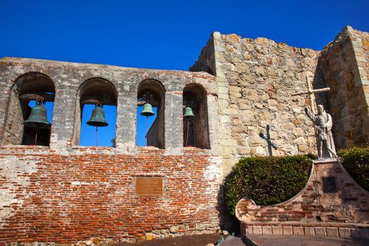 Mission San Juan Capistrano Church Ruins in California.  Brass Bells and Statue of Father Junipero Serra, who founded the Mission in 1775.  Church was destroyed in 1812 by earthquake.