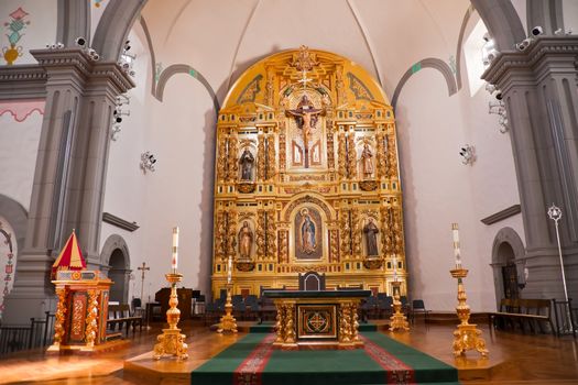 Golden altar and White Candles at Mission Basilica San Juan Capistrano Church California.  This is the successor church to the Mission founded by Father Junipero Serra in 1775.