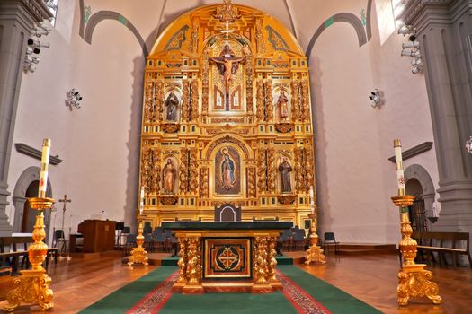Golden altar and White Candles at Mission Basilica San Juan Capistrano Church California.  This is the successor church to the Mission founded by Father Junipero Serra in 1775.