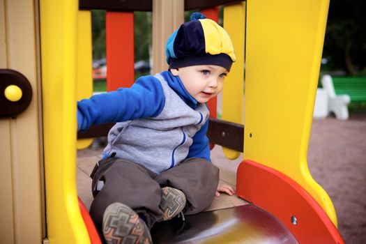 little boy playing on toy hill at playground