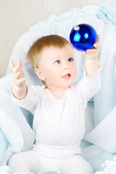baby in cradle playing with christmas ball