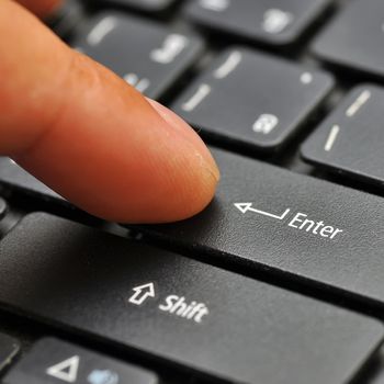 Finger on computer keyboard at enter key