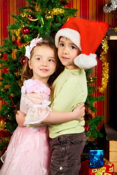 two beautiful child stand near christmas tree