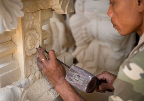 BALI, INDONESIA - SEP 21: Stone mason at work carving an ornamental relief on Sep 21, 2012 in Batubulan, Bali, Indonesia. Batubulan is a center of Balinese stone carvings art.