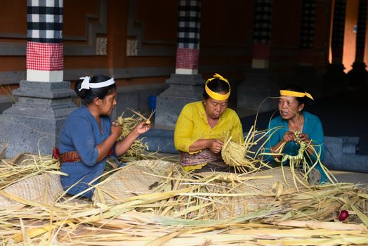 TAMPAK SIRING, BALI, INDONESIA - SEP 21: Women make baskets for balinese traditional offerings to gods in temple Puru Tirtha Empul on Sep 21, 2012 in Tampak Siring, Bali, Indonesia