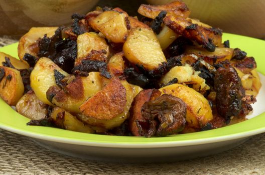 Traditional Roasted Potato with Mushrooms, Onion and Spices on Green Plate close up