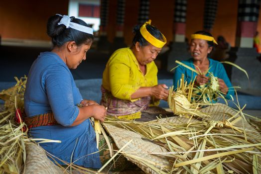 TAMPAK SIRING, BALI, INDONESIA - SEP 21: Women make baskets for balinese traditional offerings to gods in temple Puru Tirtha Empul on Sep 21, 2012 in Tampak Siring, Bali, Indonesia