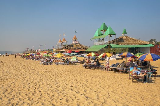 Horizontal capture at a busy beach of holidaymakers and vacationers relaxing and chilling in Goa India