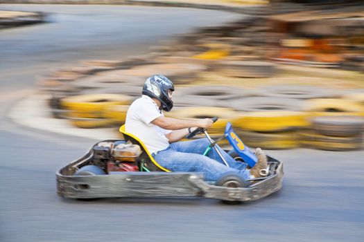 Horizontal take of an Asian driver and go kart as they zoom past on a public race track in Goa India