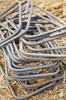 Vertical capture of wrought iron rods used in the construction industry as concreting ties. Generic shot taken in Maharashtra, India of the rectangular shapes laid on a dry grass ground