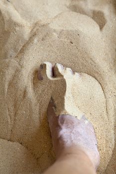 Any orientation capture of a right foot partially covered in beach sand. Generic shot location Goa, India.