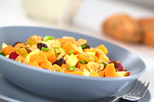 Fresh salad made of cooked sweet potatoes, fresh apples, nuts, raisins and shallots (Selective Focus, Focus one third into the salad)