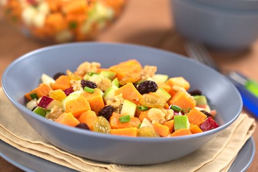 Fresh salad made of cooked sweet potatoes, fresh apples, nuts, raisins and shallots (Selective Focus, Focus one third into the salad)