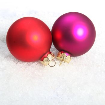 Christmas shiny red and violet globes in snow, close up