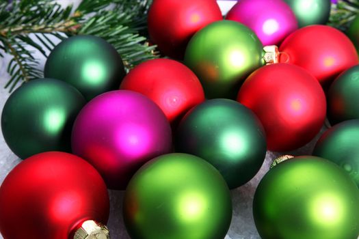 Colourful Christmas bauble background with a collection of multicoloured balls and sprigs of fir foliage