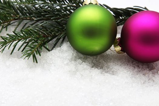 Colorful Christmas baubles, green and fuchsia on white snow
