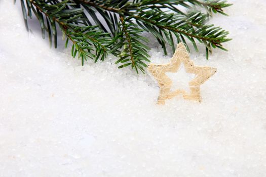 White Christmas star ornament with pine needles on snow