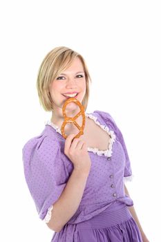 Portrait of a blond in a lavender dirndl dress and holding a bretzel. On white