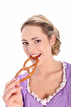 Beautiful blonde woman wearing a Bavarian style purple blouse biting a pretzel with a lovely smile isolated on white