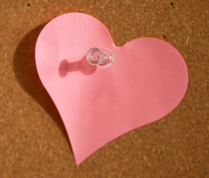 A heart shade sticker is pinned on a cork board