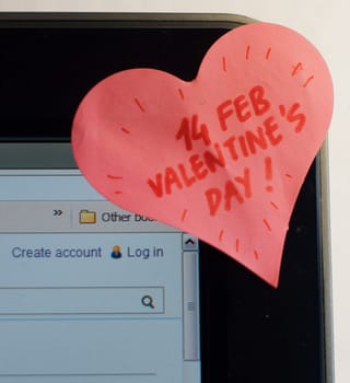 A heart shaped sticker is on a PC monitor and written valentine's day reminder on