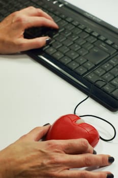 A lady holds a heart shaped mouse for on-line dating