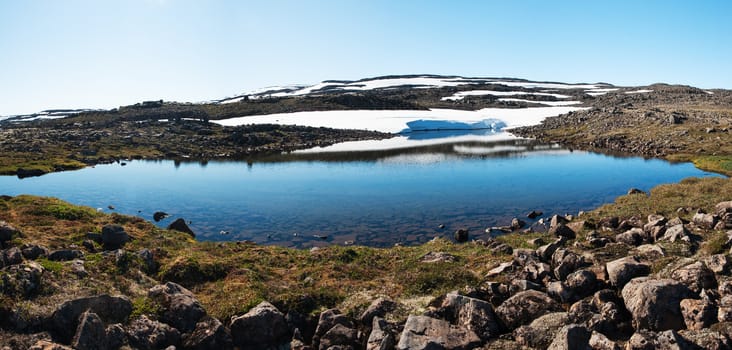 Panoramic photo of a mountain glacial lake on West Fjords peninsula, Iceland