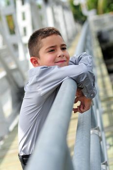 Cute young boy hanging out outoodrs on bridge