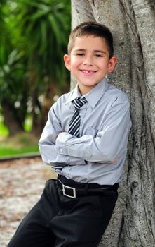 Happy Young boy leaning in business attire smiling with missing tooth