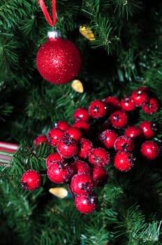 red holiday berries and ornaments on a lit christmas tree