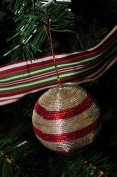 red and silver ornament hanging on a christmas tree with a ribbon accent