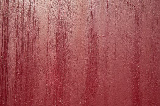 A background of red cracked and flaky  paint with vertical tones.