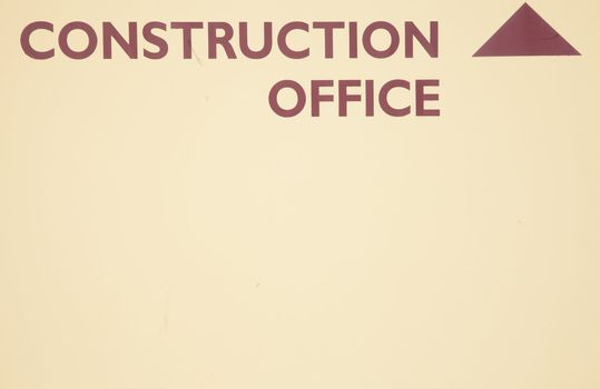 A cream background with the words 'CONSTRUCTION OFFICE' and an arrow painted in red.