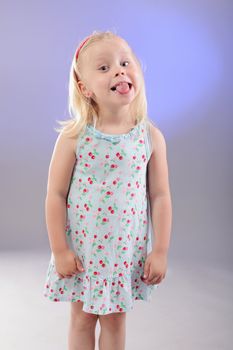 cute little blond girl posing against blue background