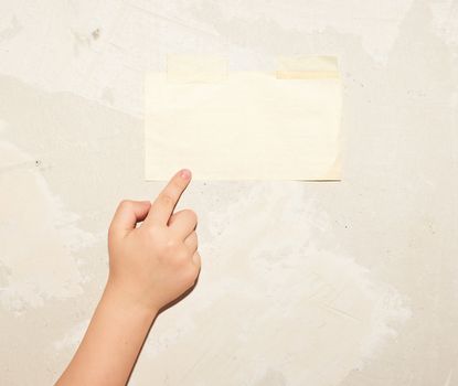 Child's hand pointing to the sheet of paper on the wall