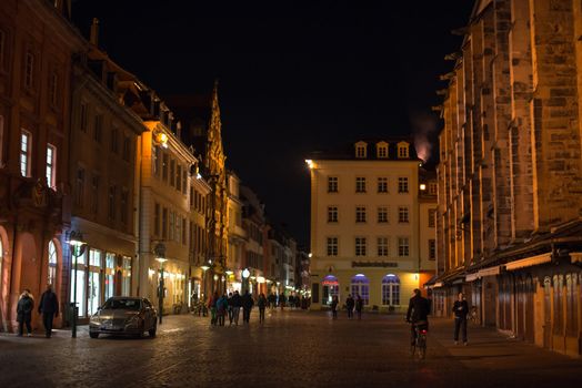 Heidelberg, Germany - February 2, 2013: Tourists walking through the centre of Heidelberg, Germany with its beautiful medieval houses in the evening of February 2, 2013. Heidelberg is a well-known tourist attraction due to its old history and beautiful location at the Neckar river.