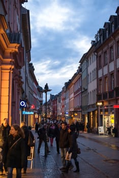 Heidelberg, Germany - February 2, 2013: Tourists walking through the centre of Heidelberg, Germany with its beautiful medieval houses in the evening of February 2, 2013. Heidelberg is a well-known tourist attraction due to its old history and beautiful location at the Neckar river.