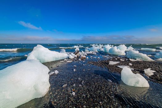 Beautiful beach in the South of Iceland with a black lava sand is full of icebergs from glaciers not far away.