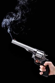 hand holding a revolver with smoking barrel, against black background