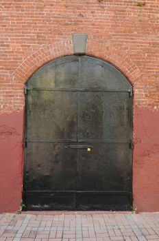 red brick building with black doors with padlock to keep out