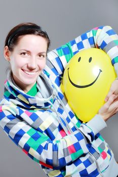 girl with a yellow smiley balloon against grey background