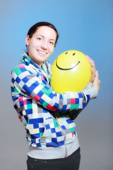 girl with a yellow smiley balloon against blue