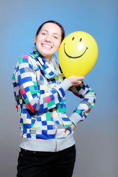 girl with a yellow smiley balloon against blue